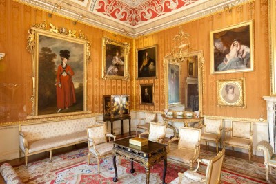 Family portraits hang on silk covered walls in the Cinnamon Drawing Room