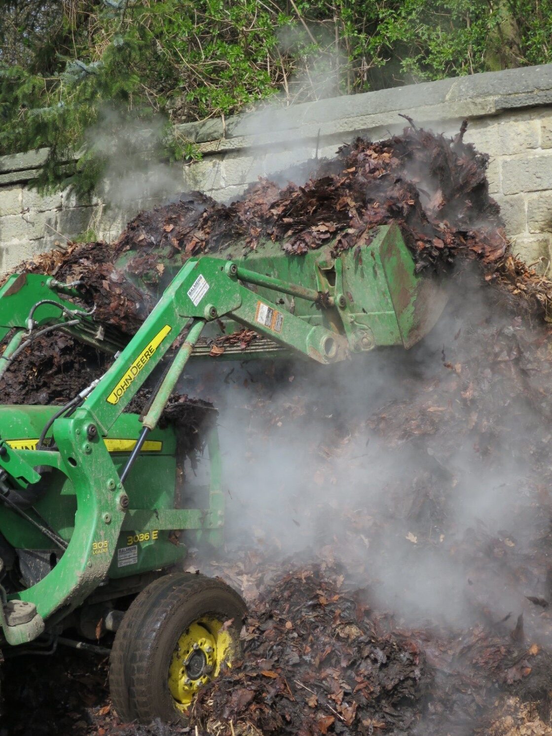 A digger carrying compost and mulch