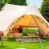 a large cream tent sits on mowed grass filled with children's toys and coloured bunting