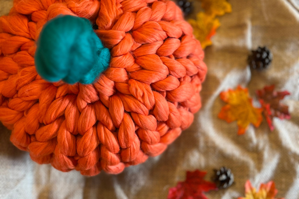 A chunky knitted pumpkin, on a table.