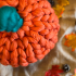 A chunky knitted pumpkin, on a table.