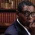 David Harewood looks at the camera with a background of library books