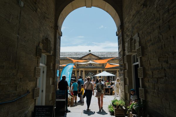 People walk through the arch into Harewood's Courtyard