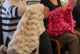 two women with thick fluffy pink and white wool around their arms