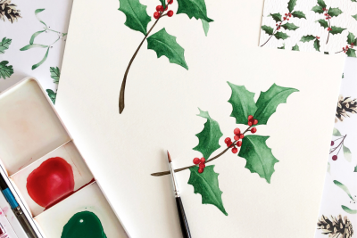 sprigs of green holly with red berries painted in watercolour on a white background