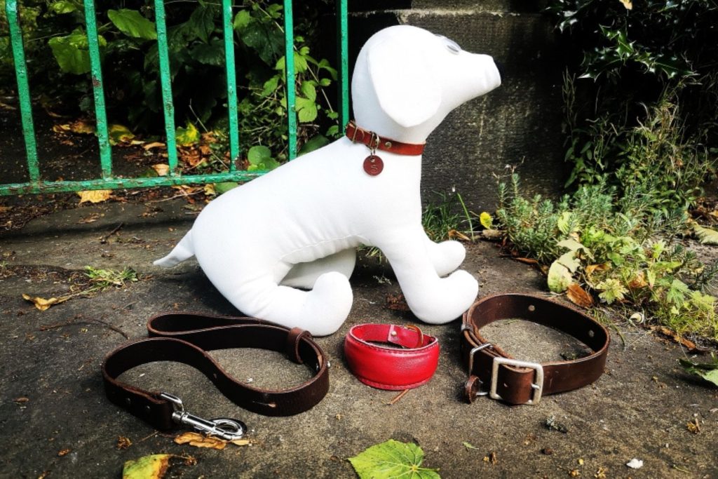 A porcelain white dog with a brown leather collar and lead in front of it