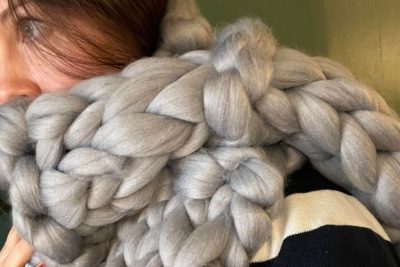 A woman wrapped up in a scarf made of chunky grey wool